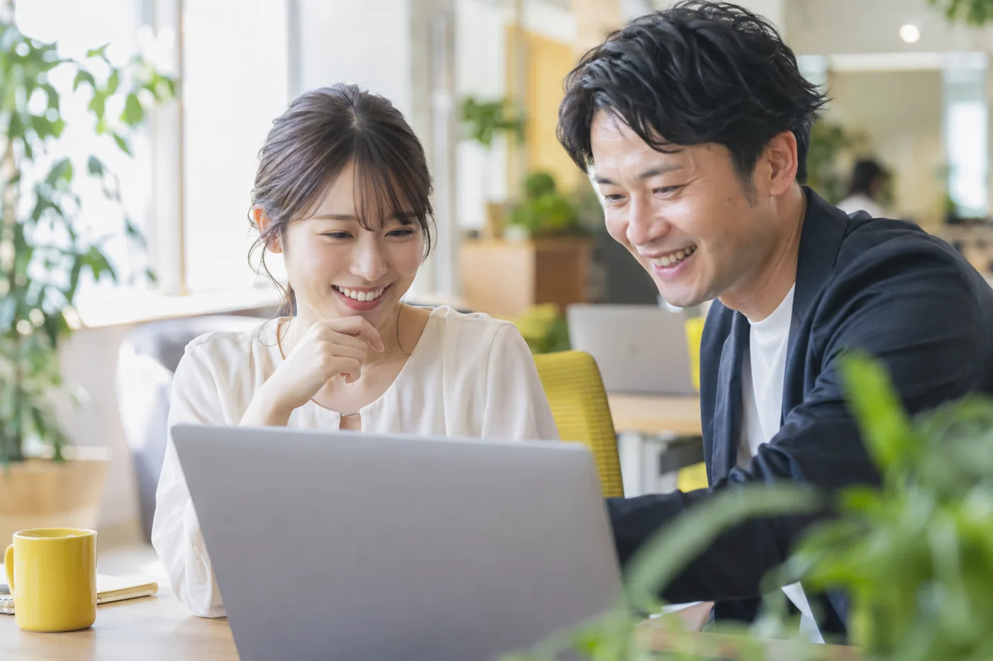 ノートパソコンを見ながら笑顔で話す2人