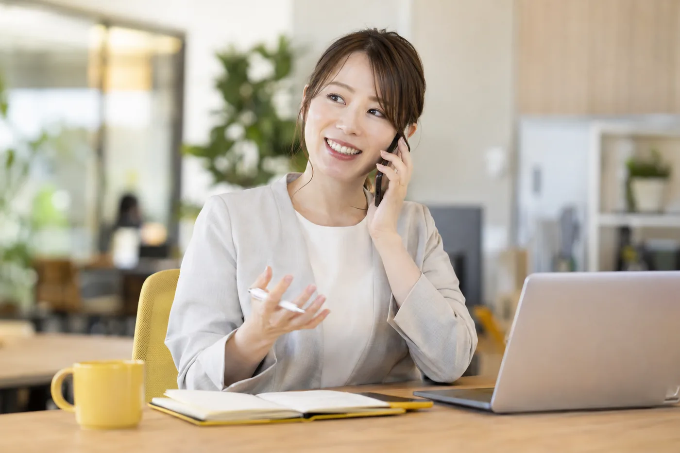 ノートを前に電話で説明する女性