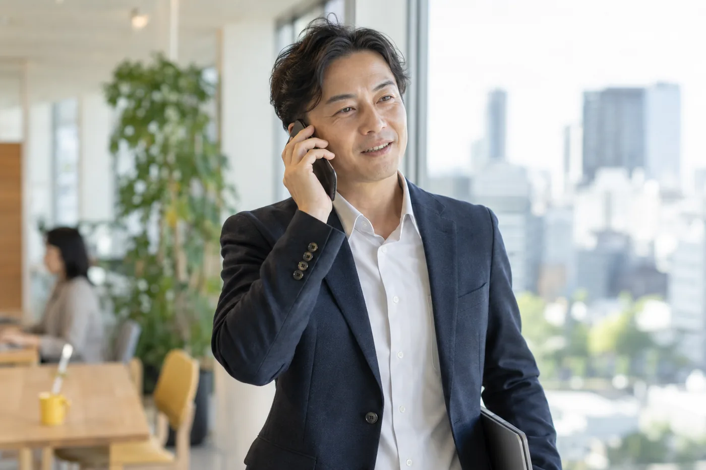 窓ぎわでスマートフォンで話す男性